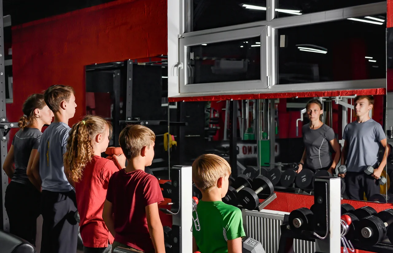FitWorks (600 x 400 px) (1280 x 823 px) Group of children and teens participating in dryland training, observing their reflection in a gym mirror